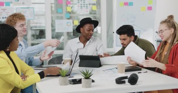 Retrato de boa aparência positiva bem-sucedida equipe diversificada altamente qualificada que trabalha com relatórios com infográficos como parte do projeto conjunto durante reunião na sala de reuniões — Vídeo de Stock