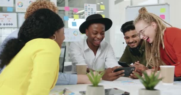 Aantrekkelijk glimlachend zelfverzekerd ervaren multiraciale kantoorvrienden die pauzeren in gezamenlijke bijeenkomst en lachen van amusante foto 's op mobiele, slow motion — Stockvideo