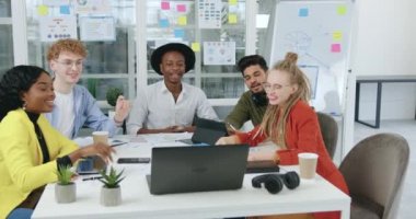 Gülümseyen, kendine güveni yüksek, yaratıcı melez bir grup iş arkadaşı, ortaklarıyla birlikte ortak proje altında çalışırken laptop 'da video konferansı yapıyor.