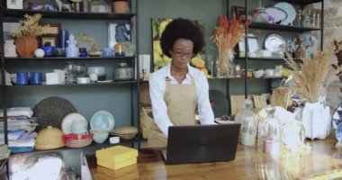 El yapımı hediyelik eşya dükkanında çalışan ve bilgisayarını kullanan güzel, konsantre olmuş Afro-Amerikan kadınının yakın çekimleri.