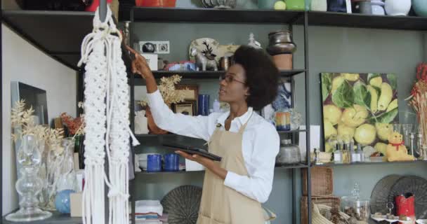 꽤 열심히 일하는 흑인 피부 여성 기념품 가게에서 상품을 회계하고 데이터를 태블릿 pc 에 기록느린 동작 — 비디오