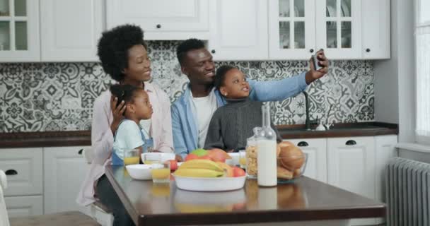 可爱的微笑快乐无忧无虑的年轻非洲裔美国家庭，孩子们在漂亮设计的厨房里用智能手机自拍，动作缓慢 — 图库视频影像