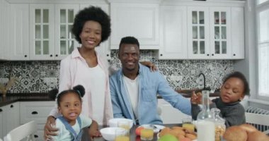 Güzel görünüşlü, güler yüzlü, modern Afro-Amerikan ailesi kamerada poz veriyor. Güzel tasarlanmış mutfak, ön manzara, 4k