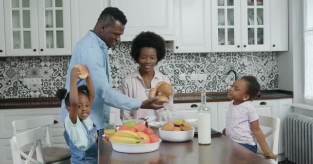Close up of adorable happy smiling african american family which have breakfast with freshly baked rolls in contemporary kitchen, 4k — стоковое видео