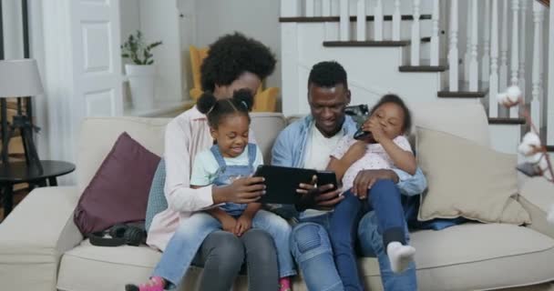 Front view of beautiful happy loving cheerful african american family which having fun together at home while revisioning funny videos on tablet pc, 4k — стоковое видео