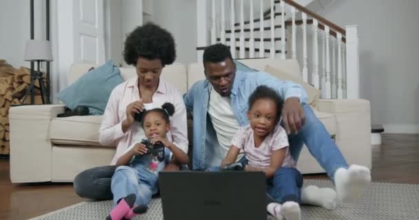 Imádnivaló elégedett boldog afro-amerikai pár két kislányával a földön ülve videojátékoznak számítógépen, családi szabadidő koncepció, 4k — Stock videók