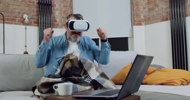 Handsome happy emotional bearded man in virtual reality headset watching video match and rejoicing the getted results with hands up,leisure concept — Stock Video