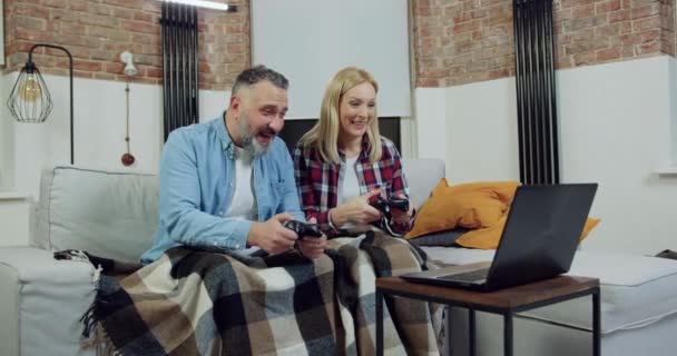 Atraente satisfeito sorrindo feliz casal adulto passar lazer conjunto em casa e jogar videogame no computador usando joysticks, vista frontal — Vídeo de Stock