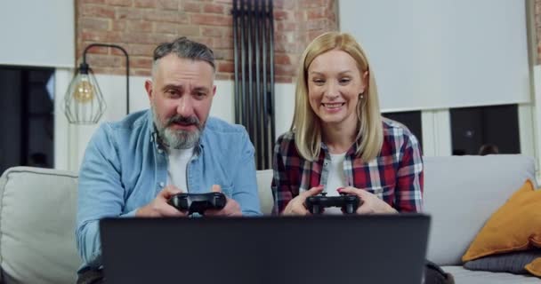 Gros plan de beau couple d'adultes heureux souriants émotionnels qui jouent au jeu vidéo sur ordinateur portable et célèbrent la victoire, se donnant cinq — Video