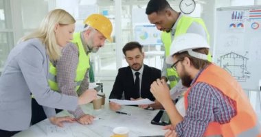 Yönetim kurulundaki toplantı sırasında kendine güvenen başarılı sakallı patronlarıyla teknik taslak ve raporları tartışan çok ırklı inşaatçılardan oluşan sevimli, yetenekli bir ekibin ön görüşü.