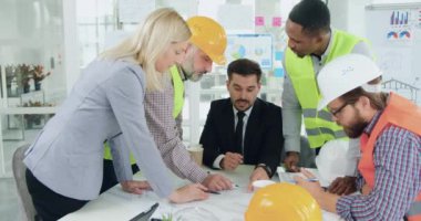 Yönetim kurulunda toplanan ve proje üzerinde beyin fırtınası yapan yakışıklı, profesyonel çok ırklı uzmanlar ve mühendisler.