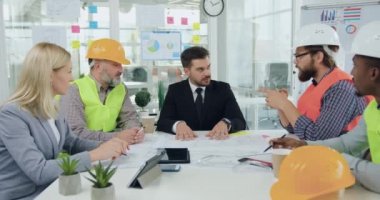 İnşaat endüstrisi konsepti. Çekici, iyi niyetli, profesyonel mühendislerden oluşan bir ekip, başarılı, sakallı bir yöneticiyle tokalaşıyor. Ortak inşaat projesinin tüm detaylarını kabul ediyor.