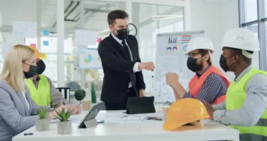 İyi görünümlü, koruyucu maskeli pozitif sakallı bir müdürün portresi profesyonel uzman melez ırkını karşılıyor. Mühendislerden oluşan bir ekip. Ayrıca brifingden önce yumruklarını yumruklayarak koruyucu maskeler takıyor.