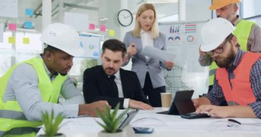 Ofis odasındaki toplantı sırasında ortak inşa projesi üzerinde çalışan çekici, kendine güvenen, etnik çeşitliliğe sahip bir grup mühendis.