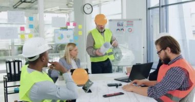 İyi görünümlü, kendine güvenen çok ırklı mühendisler ofis odasındaki toplantı sırasında ortak bina projesiyle ilgili beyin fırtınası yapıyorlar.