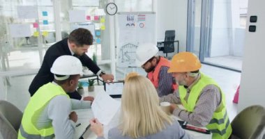 Ortak inşaat projesiyle ilgili toplantı yapan, kendine güveni yüksek, karışık profesyonel ırk müteahhitlerinden oluşan bir ekip.