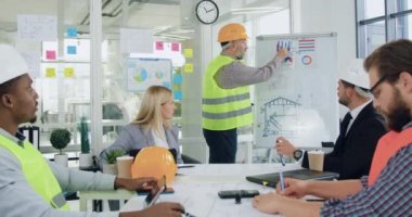 İyi görünümlü, profesyonel, çeşitli mühendisler ve inşaat şirketinin yöneticileri toplantıyı başarıyla bitirdikten sonra el çırpıyorlar.