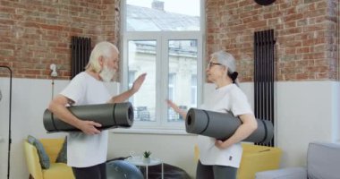 Çekici, güler yüzlü, spor giyim sektöründe son sınıf çifti evde paspaslar üzerinde egzersiz yapmaya başlamadan önce birbirlerine beşlik çakıyor.