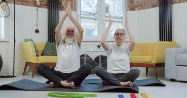 Spor giyimli, sakin ve aktif bir çift evde yoga yaparken nefes egzersizi yapıyor. Kapatın, yavaş çekim.