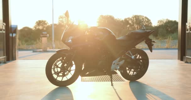 Imagen atractiva de la motocicleta moderna y costosa que se encuentra bajo los rayos del sol en la plaza de hormigón — Vídeos de Stock
