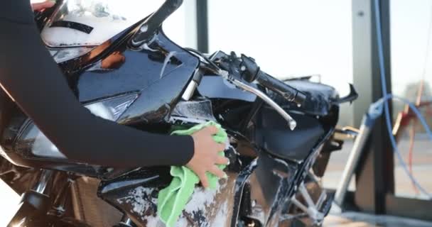 Vacker snygg ung flicka i svarta kläder torka med tyg från skum hennes lyxiga svarta motorcykel på självbetjäning biltvätt, slow motion — Stockvideo