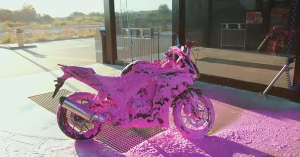 Immagine di moto moderna costosa che coperto di schiuma rosa sulla stazione di lavaggio auto al tramonto — Video Stock