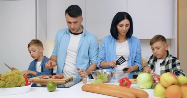 Adorable in high spirits friendly family with children preparing together delicious dinner in cozy kitchen ,front view — Stock Video