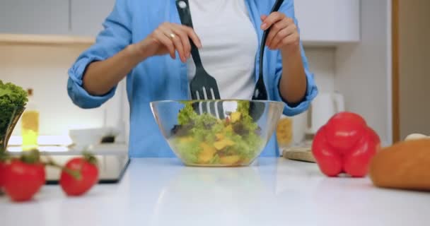 Donna moderna dall'aspetto sconosciuto che mescola insalata di verdure fresche in una ciotola di vetro per la cena in famiglia in cucina contemporanea, primo piano — Video Stock