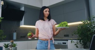 Güzel görünüşlü, gülümseyen, elinde marul ve mango olan 30 'lu yaşlarda bir esmer. Onlardan birinin lehine nasıl seçim yapacağına karar veriyor.