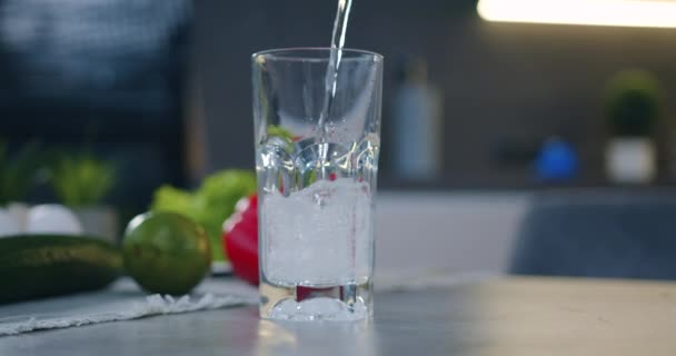 Vista frontale di vetro trasparente che è riempito con acqua dolce sullo sfondo della cucina — Video Stock