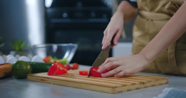 未知の主婦は夕食時に彼女の家族のための新鮮な野菜サラダを準備しながらナイフを使用してまな板の上に小さな部分赤唐辛子をスライス — ストック動画
