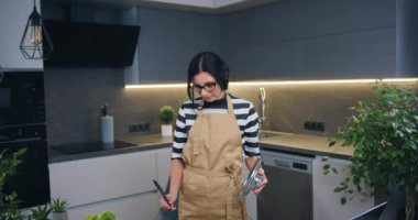 Güzel bir gülümseme önlüklü genç bir kadın çorba hazırladı ve onu modern mutfakta tattı, ev yapımı hazırlık konsepti, ön manzara