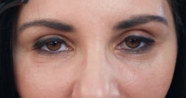 Çekici, kendinden emin, mutlu, ela gözlü, siyah saçlı kadınların portresi kameraya şık bir gözlük takıyor, resim gözlere odaklanıyor.