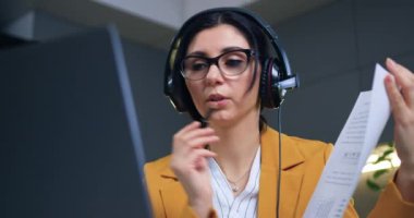 İyi görünümlü, kendine güvenen, kulaklıklı, siyah saçlı başarılı iş kadınının partnerleriyle görüntülü konuşma yaptığı ve veri raporlarını analiz ettiği ev konseptinden uzakta çalışıyorum.