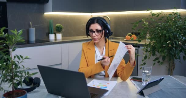 Çevrimiçi video konferansı düzenleyen 35 yaşında başarılı modern iş kadını ev mutfağında otururken veri raporlarını açıklıyor. — Stok video