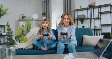 Güzel duygusal iki kız kardeş-büyük ve genç kız kardeş video oyunları oynayarak vakit geçiriyorlar ve bu oyunu kaybetmekten memnun olmuyorlar, ağır çekimde.