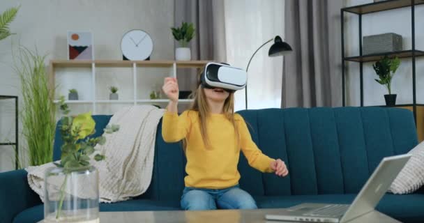 Retrato de niña de 10 años muy guapa sonriente emocionada que disfruta de entretenimiento virtual en gafas especiales 3d mientras está sentada en un sofá suave en casa — Vídeos de Stock