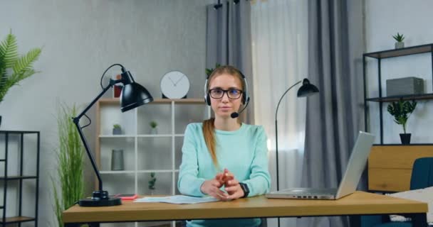 良い気分で可愛いの肖像笑顔20歳の女の子ヘッドセットこれは、オンラインビデオ会議後に眼鏡を取りながらカメラにポーズ — ストック動画