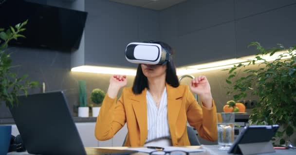 Portrét sympatické sebevědomé a úspěšné dospělé tmavovlasé ženy ve stylové bundě, která pracuje na virtuální obrazovce ve speciálních 3D brýlích doma — Stock video