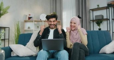 Mutlu, neşeli, çekici, genç Arap çift zaferi kutluyorlar. Bilgisayarda el kaldırarak ve beşlik çakarak, ağır çekimde.