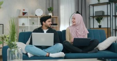 Sevimli gülümseyen genç adam ve tesettürde oturan nilüferli bayan arkadaşı kanepede oturup birbirleriyle konuşuyorlar ve sonra kapalı gözlerle meditasyon yapmaya başlıyorlar.