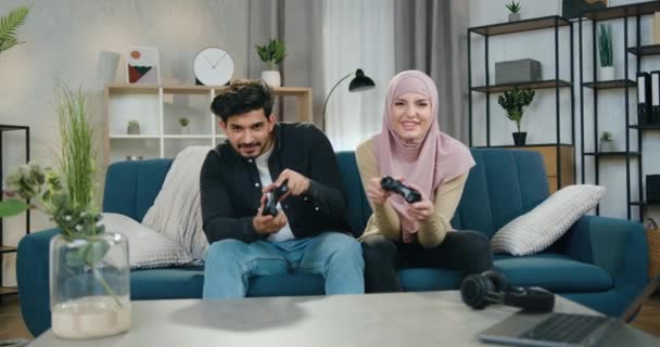 Vrolijk amusant aantrekkelijk jong multi-etnische paar genieten van videospelletjes en geven high five elkaar toen ze het spel won, familie vrijetijdsconcept — Stockvideo