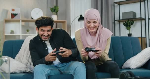 Flot tilfreds skægget fyr fejrer sejr i videospil, mens hans arabiske kæreste i hijab er trist becouse hun tabte spillet, fritid koncept – Stock-video