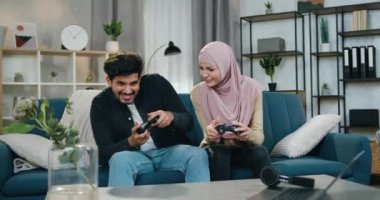 Sevimli, komik, 30 yaşında Arap bir çift oyun kağıtlarıyla video oyunu oynarken eğleniyor, kadın zaferi kutluyor ve erkek kaybettiği için mutsuz.