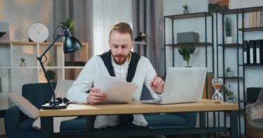 Çekicilikten bıkmış, iş sakallı ofis kadınına odaklanmış. Ev ofisinde dizüstü bilgisayar ve kağıtlar üzerinde çalışıyor. Sonra da baş ağrısı yüzünden şakaklara masaj yapıyor.