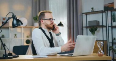 Çekici bir gülümseme. 30 yaşında, evli, sakallı bir ofis çalışanı ev bilgisayarında çalışırken telefonla konuşuyor.