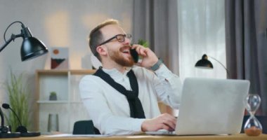 Gözlüklü yakışıklı, sakallı, şakadan kahkahalar atan. Evde dizüstü bilgisayarla çalışırken, iş yerinden birinden telefon alan.