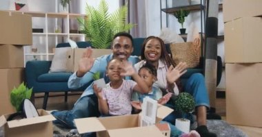 Çekici, neşeli, mutlu, Afro-Amerikan bir aile. İki küçük çocuk yerde, yeni edinilmiş bir dairede oturuyor. Bir sürü kutunun arasında el sallıyorlar.