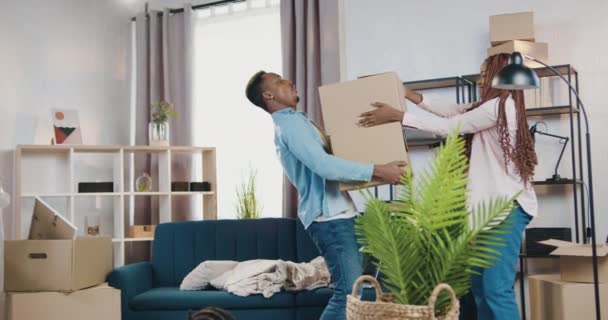 Concept immobilier où de beaux jeunes afro-américains forts tenant des boîtes en carton qui lui donnent sa femme moderne avec dreadlocks jour de déménagement dans un appartement nouvellement acquis — Video
