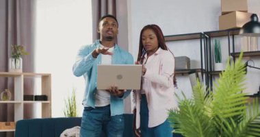 Kendine güveni tam genç bir Afro-Amerikan çifti yeni edinilmiş bir dairede duruyor ve tasarım fikirleri olan internet sitelerini kullanarak odayı döşemeyi planlıyor.